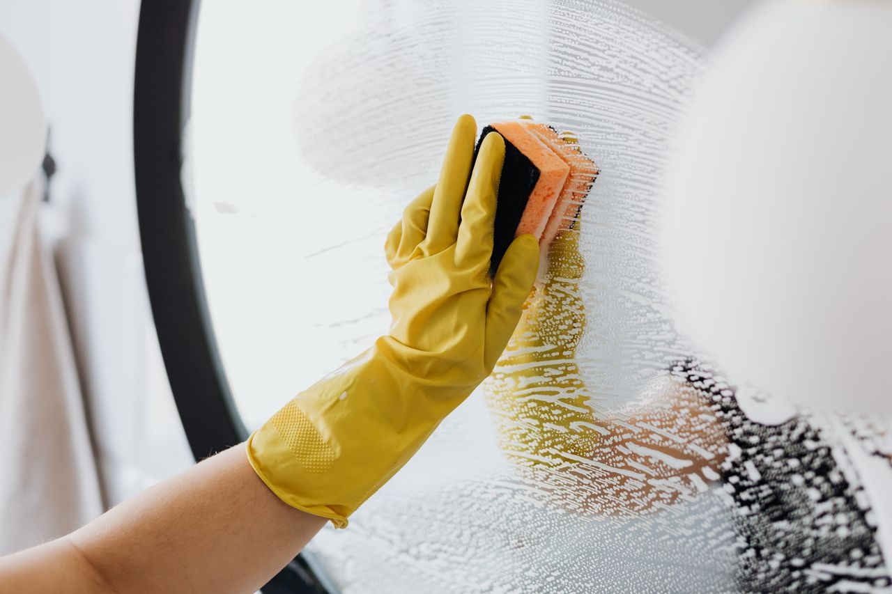 The Art of Drawing Readers In: Your attractive post title goes here Anonymous person in yellow rubber gloves using simple sponge for cleaning mirror in bathroom